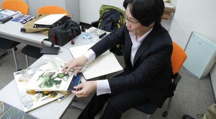 Masayuki Suzuki (in the green jacket) and Satoshi Nakai (in the suit) leaf through some artwork relating to their past titles