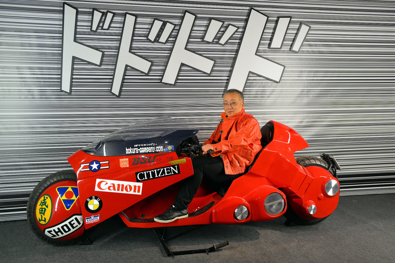Katsuhiro Otomo, o criador de Akira, posa com a motocicleta de Kaneda no Festival Internacional de Quadrinhos de Angoulême —Imagem: Selbymay/Wikimedia Commons