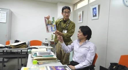 Masayuki Suzuki (in the green jacket) and Satoshi Nakai (in the suit) leaf through some artwork relating to their past titles